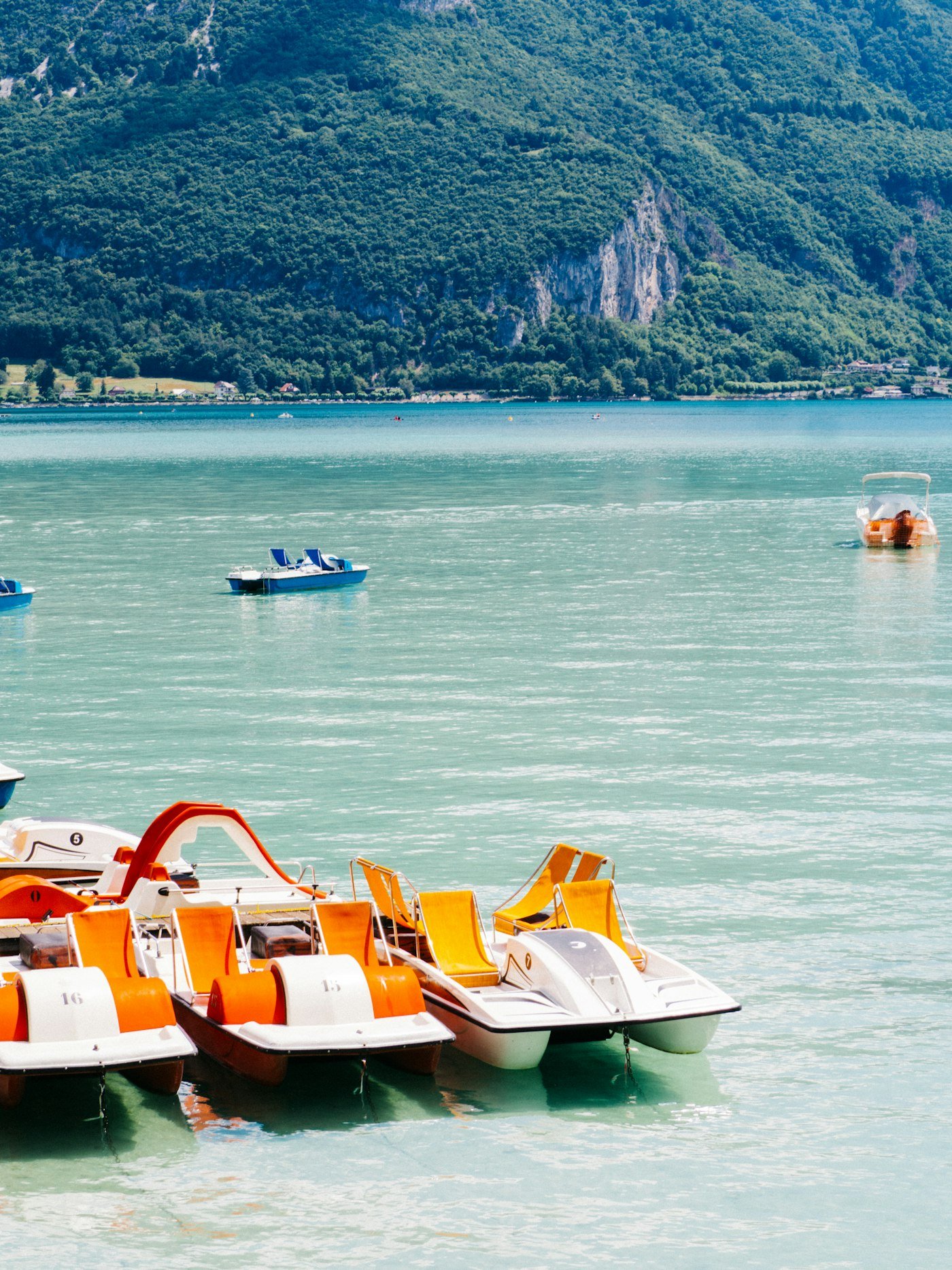 Pédalos alignés au bord de l'eau turquoise du lac d'Annecy