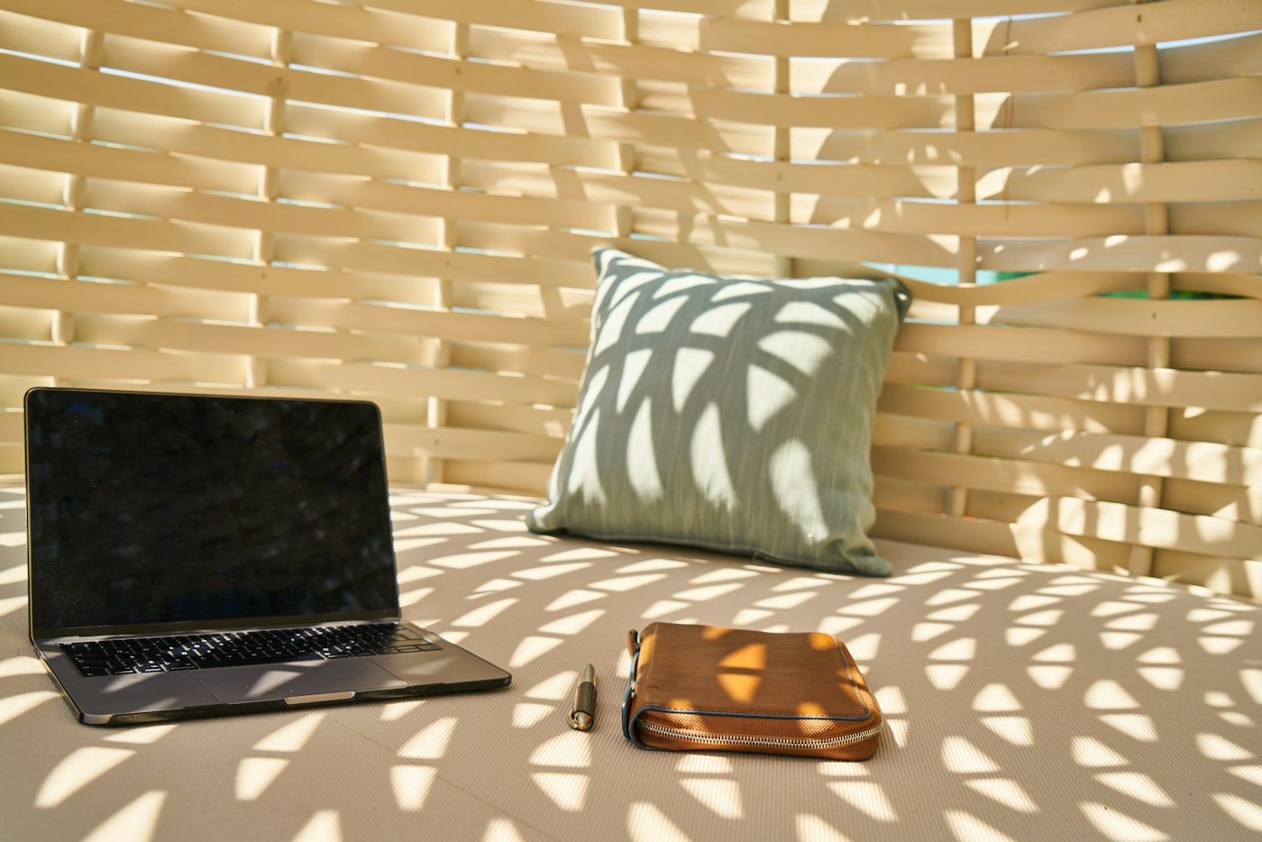 Ordinateur portable et pochette posés sur un lit, lumière de fin de journée